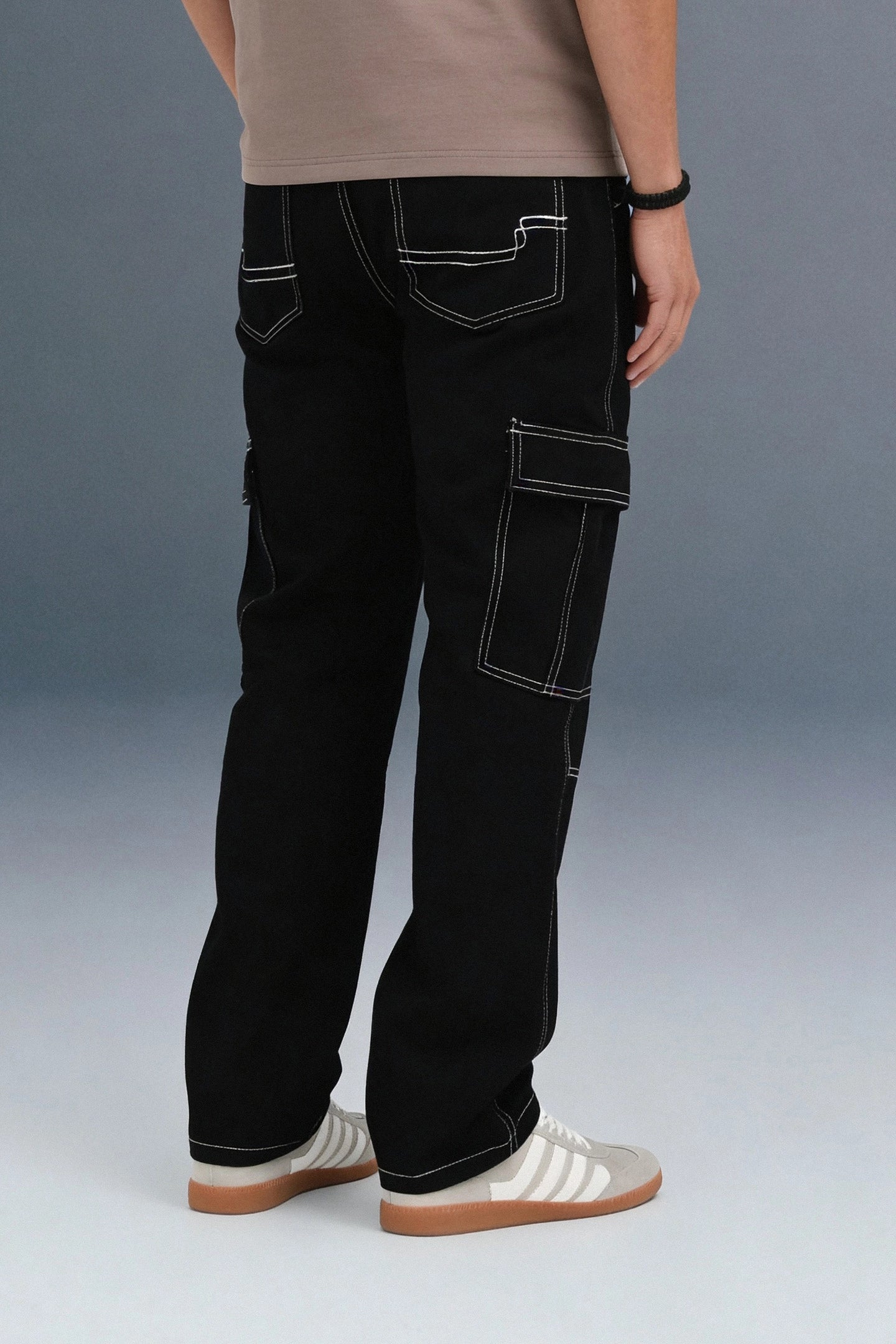 Back view of black cargo jeans showing the white stitching on the rear pockets and side utility pockets.