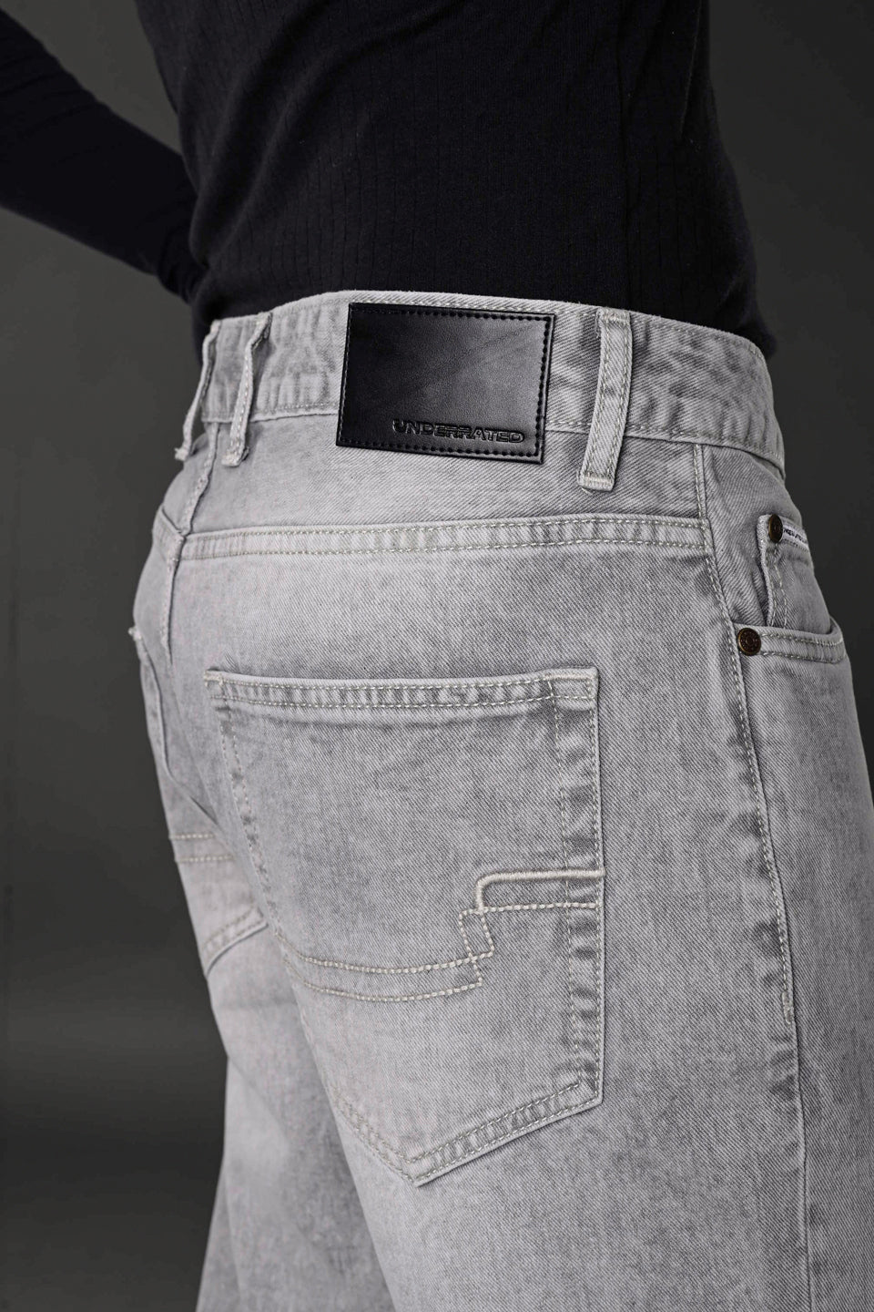 Grey denim jeans back pocket black leather Underrated Club label stitching detail men's fashion.