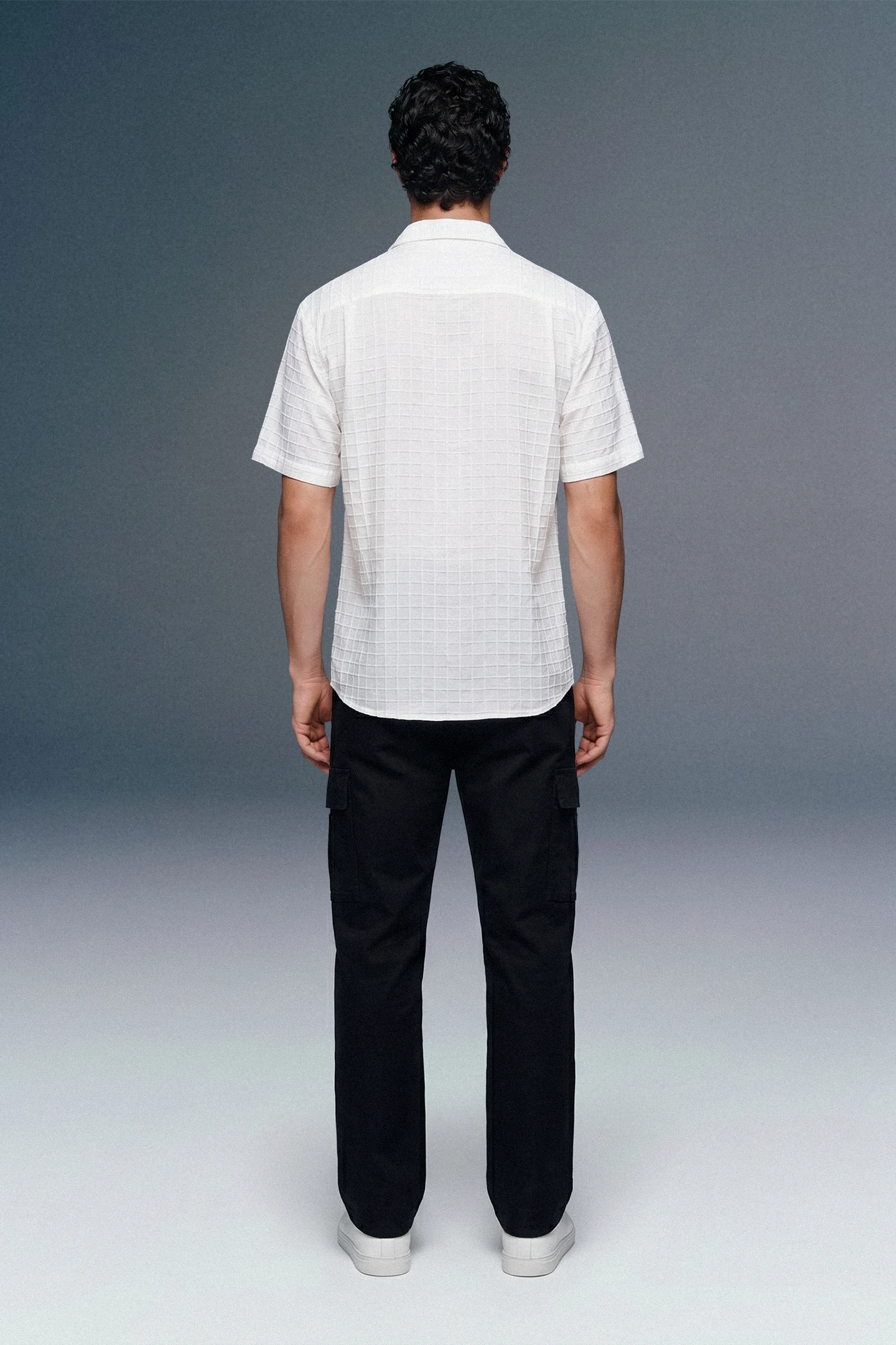 Person wearing a white shirt and black pants on a gray background