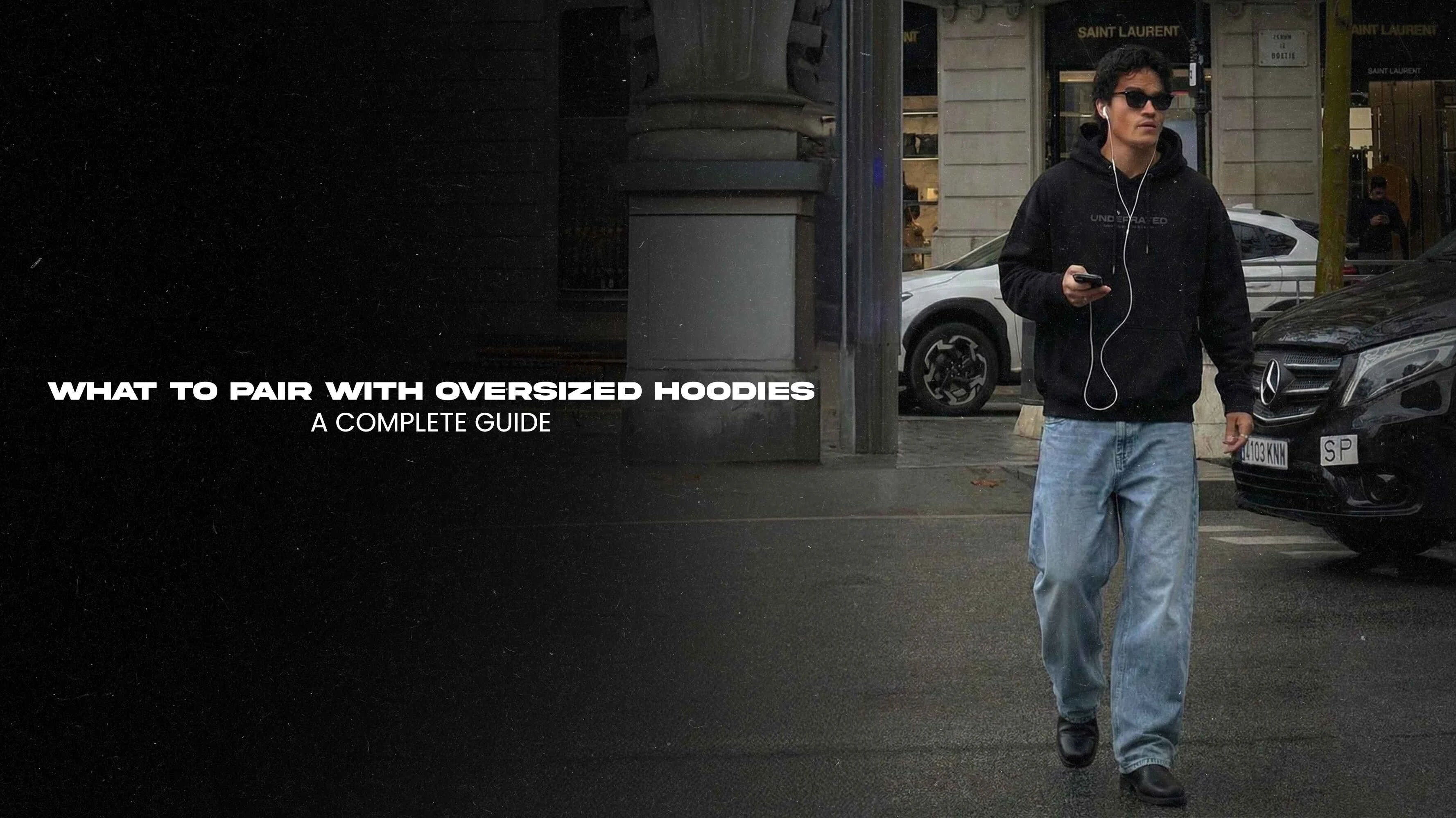 Streetwear thumbnail "What to Pair with Oversized Hoodies: A Complete Guide" black hoodie model sunglasses earphones baggy blue jeans urban street cars luxury Mercedes.