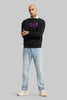 Front view of a man standing in a black sweatshirt with a multi-colored red and blue graphic on the chest.