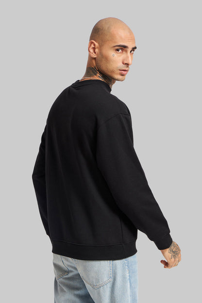 Rear view of a man wearing a plain black crewneck sweatshirt and light blue jeans, standing against a solid grey studio background.
