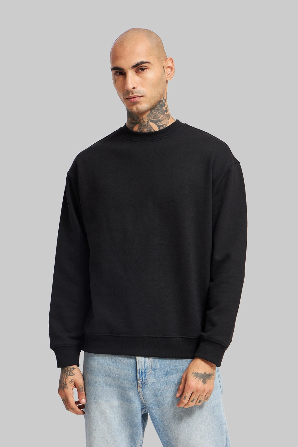 Back view of a man in a black oversized sweatshirt, showcasing the relaxed drop-shoulder fit and clean silhouette.