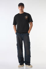 Man right profile side view in black oversized t-shirt, head turned, plain background.