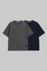 Two short-sleeve crewneck t-shirts displayed side by side on a solid gray background. The front t-shirt is dark gray, and the t-shirt behind it is navy blue.