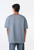 Man back view wearing light grey oversized crew neck t-shirt, standing straight against white studio background.
