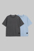 Two short-sleeve crewneck t-shirts displayed side-by-side against a solid gray background. The front t-shirt is dark charcoal gray, and the t-shirt behind it is light blue.
