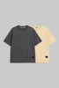 Two plain short-sleeve crew-neck T-shirts on a light gray background, shown overlapping. The front shirt is dark charcoal gray, and the shirt behind it is pale cream/yellow.