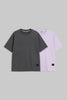 Two short-sleeve crewneck t-shirts displayed side-by-side on a solid gray background. The front t-shirt is dark charcoal gray, and the t-shirt behind it is light lavender purple.