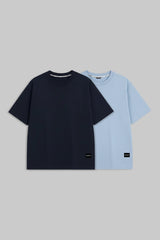 Two short-sleeve crew-neck t-shirts displayed flat against a solid gray background. The front t-shirt is solid navy blue, and the t-shirt behind it is solid light blue.