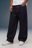 A person wearing very wide-leg dark indigo denim jeans with contrast tan stitching, styled with a white t-shirt and white sneakers against a studio backdrop.