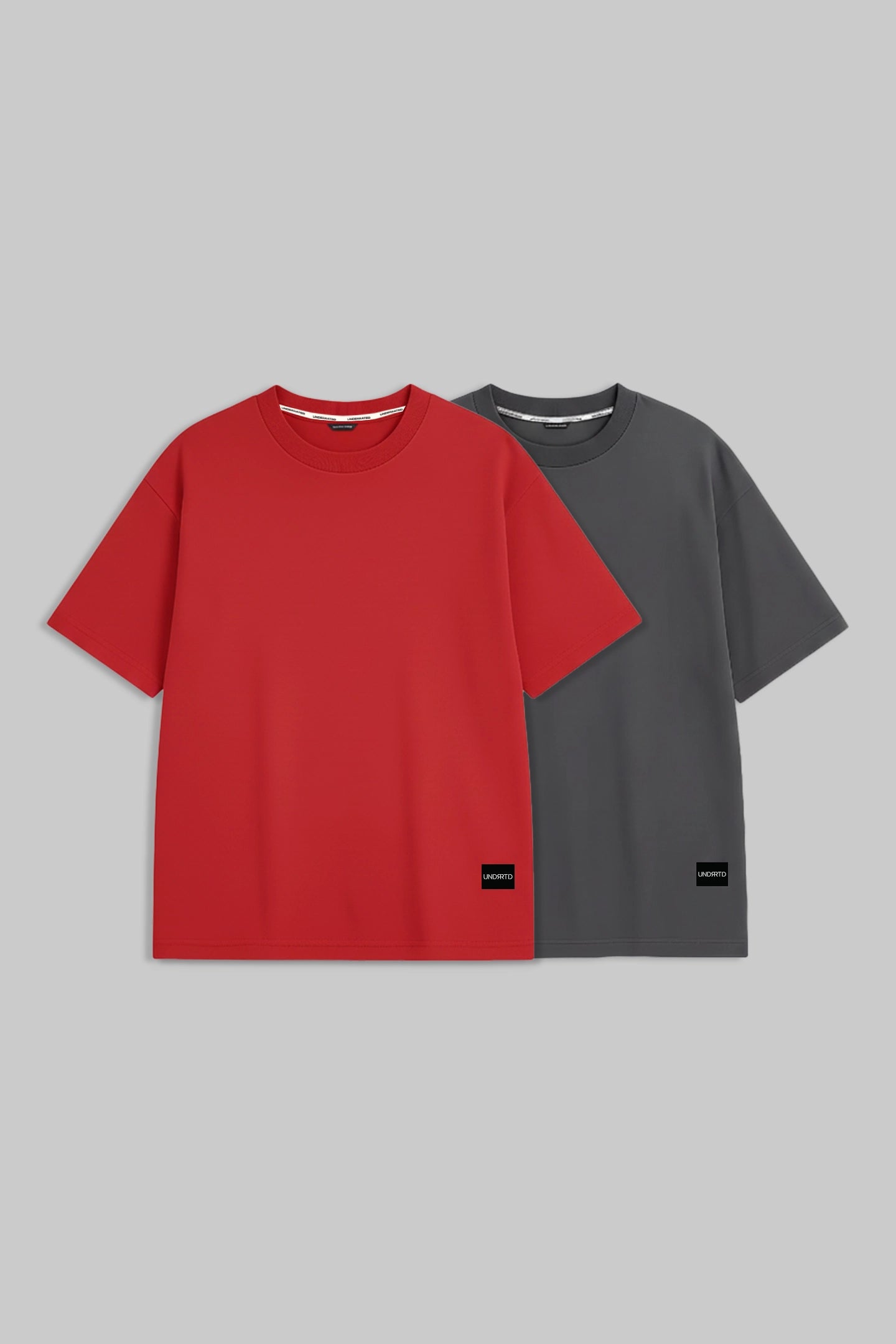 Two short-sleeve crewneck t-shirts displayed side by side on a solid gray background. The front t-shirt is a vibrant red, and the t-shirt behind it is dark gray.