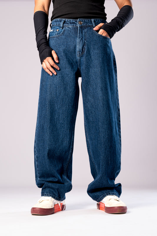 Angled back view of a person wearing baggy, dark blue jeans, highlighting the fit and style.