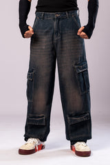 Full-body front view of a person wearing dark, rusty-blue baggy cargo jeans with a black top and black arm sleeves, with their hands clenched.