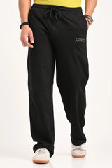 A man wearing black relaxed-fit drawstring trousers with a small 