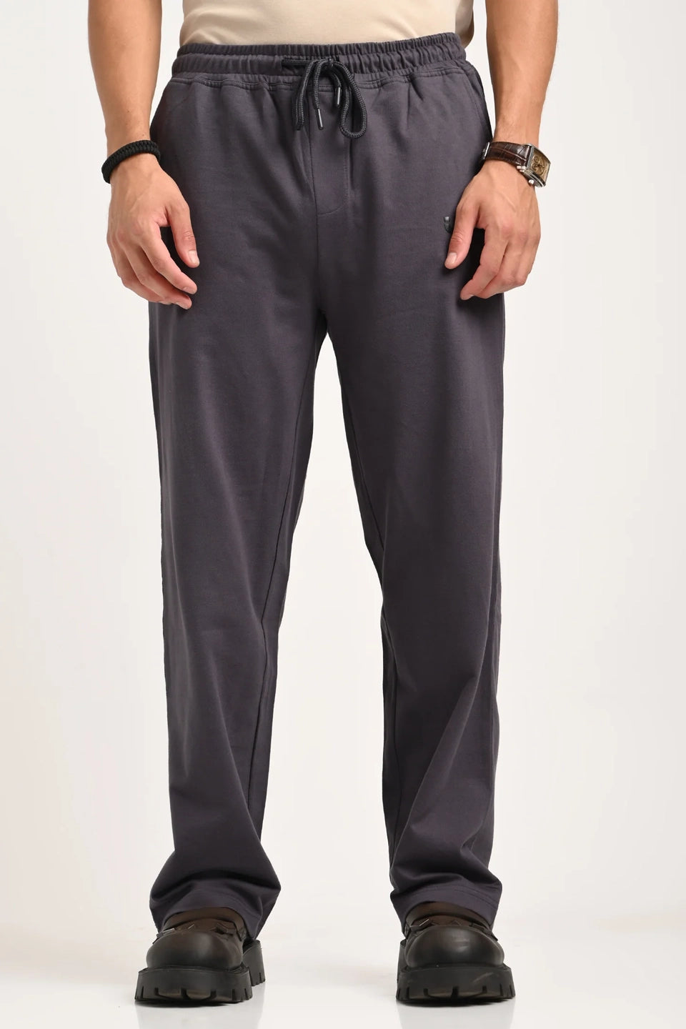 A man wearing black relaxed-fit drawstring trousers with a small "URC" logo and white sneakers.