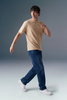 Man wearing a beige t-shirt and blue jeans on a gray background