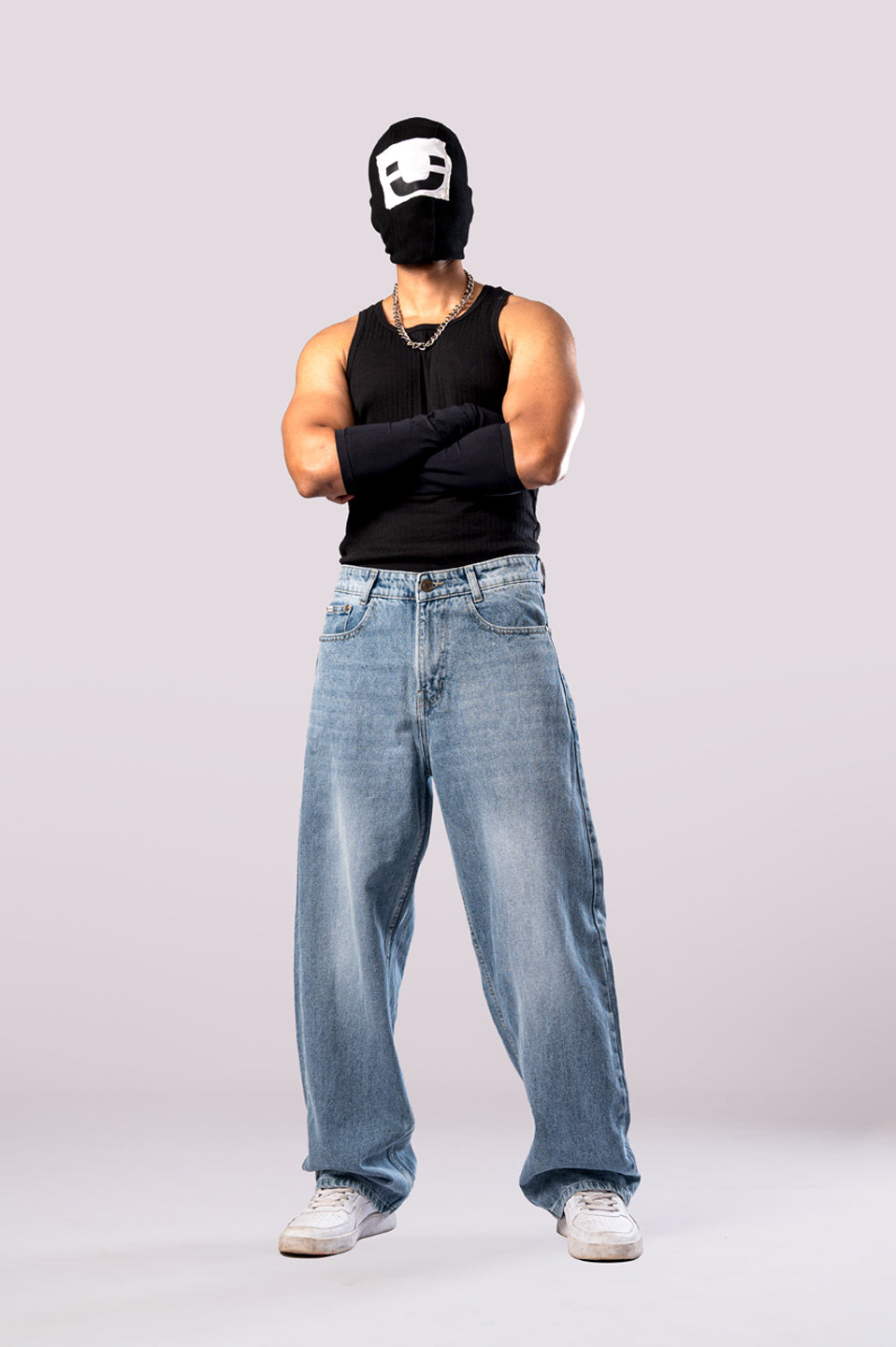 Full-body shot of the model in light wash baggy jeans, arms crossed.