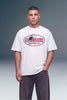 A man wearing a white crewneck t-shirt with a red and blue 'Unbranded Machine Co.' graphic on the chest, paired with dark gray jeans, against a studio background.