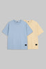 Two short-sleeve crewneck t-shirts displayed side-by-side on a solid gray background. The front t-shirt is light blue, and the t-shirt behind it is pale yellow.