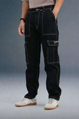 Close-up of the front of black cargo pants, emphasizing the white stitching and large side pockets.