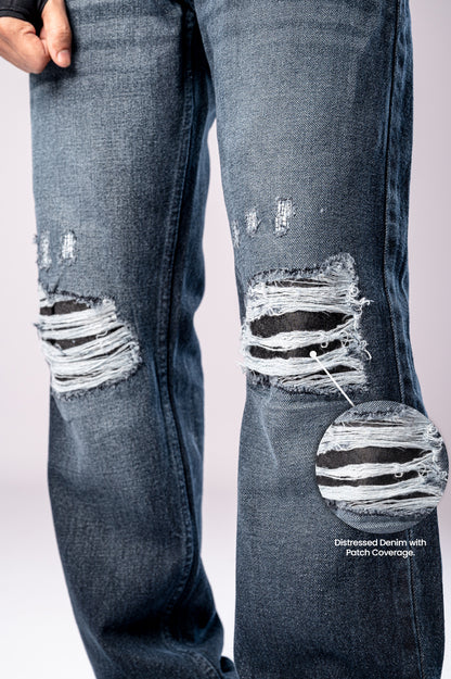 Close-up of the ripped knees on a pair of dark-wash blue jeans, with a circular inset magnifying the distressed fabric.