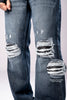 Close-up of the ripped knees on a pair of dark-wash blue jeans, with a circular inset magnifying the distressed fabric.