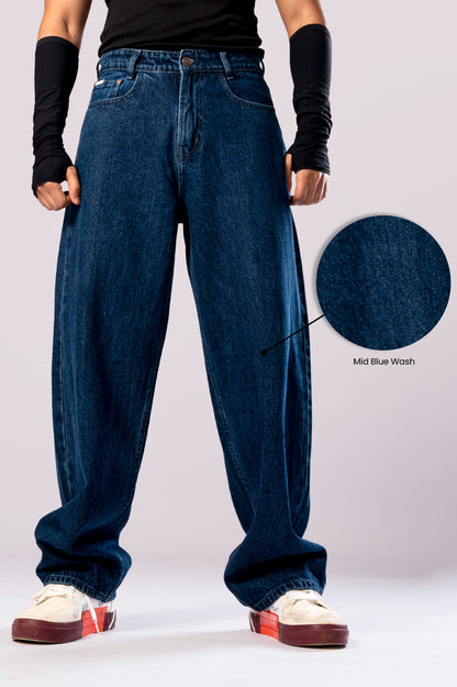 Full-body view of a person wearing baggy, dark blue jeans with the cuffs rolled up, with a circular inset showing a close-up of the fabric's texture.