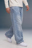 A person wearing light-wash, wide-leg denim jeans with a faded wash, styled with a cream long-sleeve shirt and white sneakers against a studio backdrop.