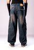 Full-body back view of a person wearing dark, rusty-blue baggy cargo jeans, a black top, and black arm sleeves, showing the loose fit and large side cargo pockets.