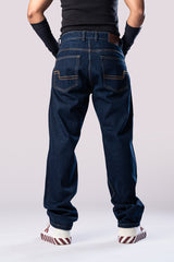 Full-body back view of a person wearing dark-wash blue baggy jeans, a black top, and black arm sleeves.