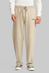 A man wearing beige relaxed-fit drawstring trousers with a small 