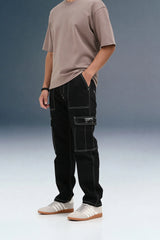 A person standing at an angle in black contrast-stitch cargo pants against a grey background.