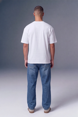A man viewed from behind wearing a plain white short-sleeve t-shirt and blue jeans, standing against a gray studio background.
