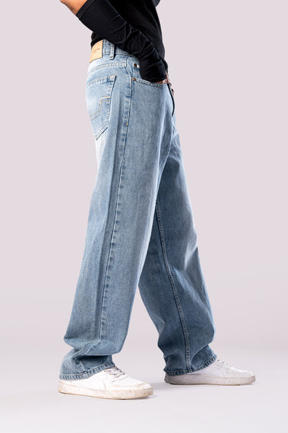Side view of light wash, wide-leg baggy denim jeans on a model with white sneakers.