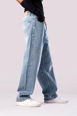 Full-body shot of the model in dark wash baggy jeans with arms crossed.