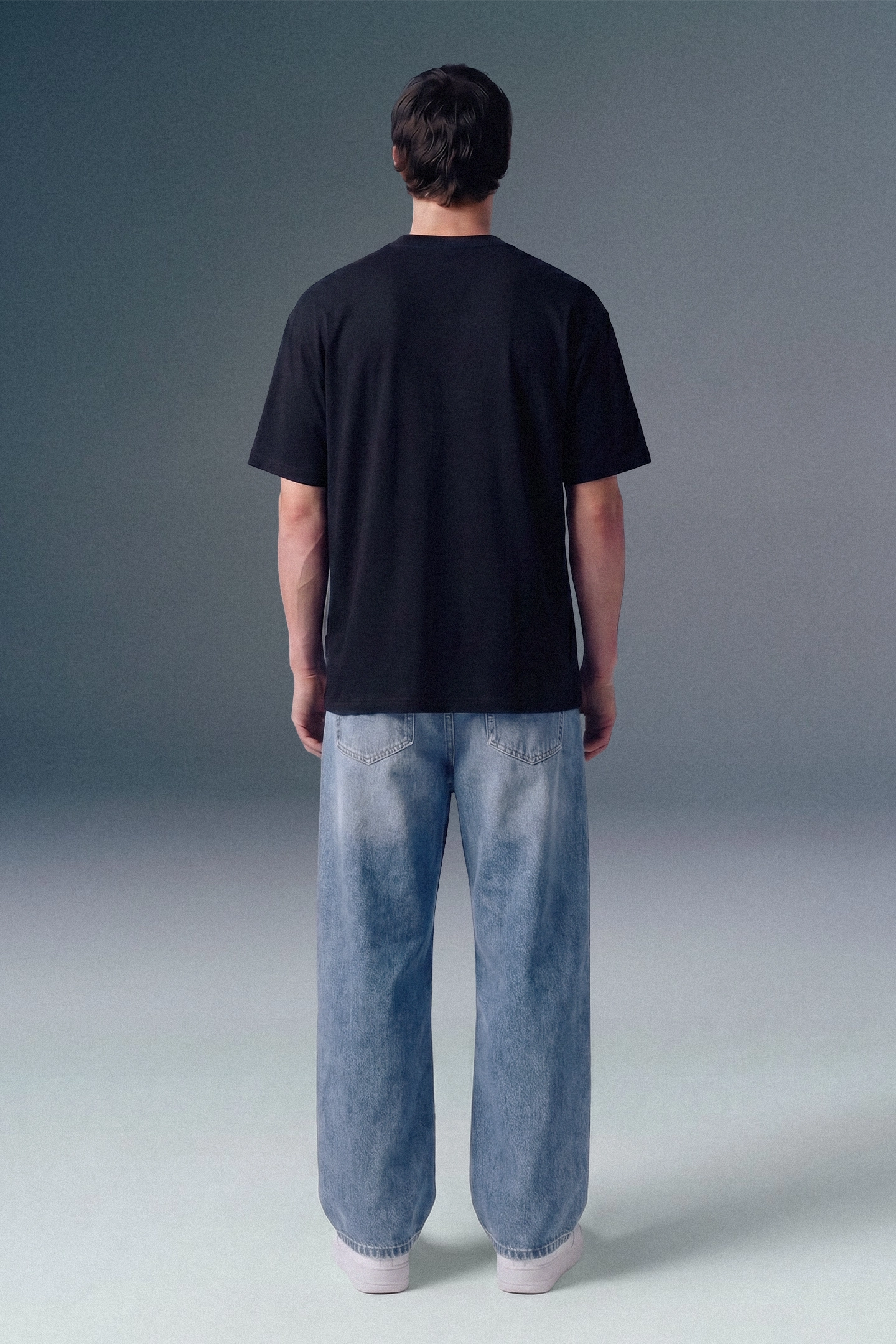 Person wearing a black t-shirt and light blue jeans against a gray background