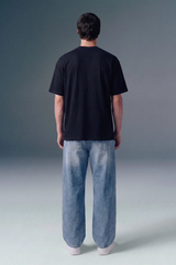 Person wearing a black t-shirt and light blue jeans against a gray background