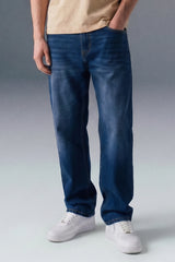 Person wearing blue jeans and white sneakers on a gray background