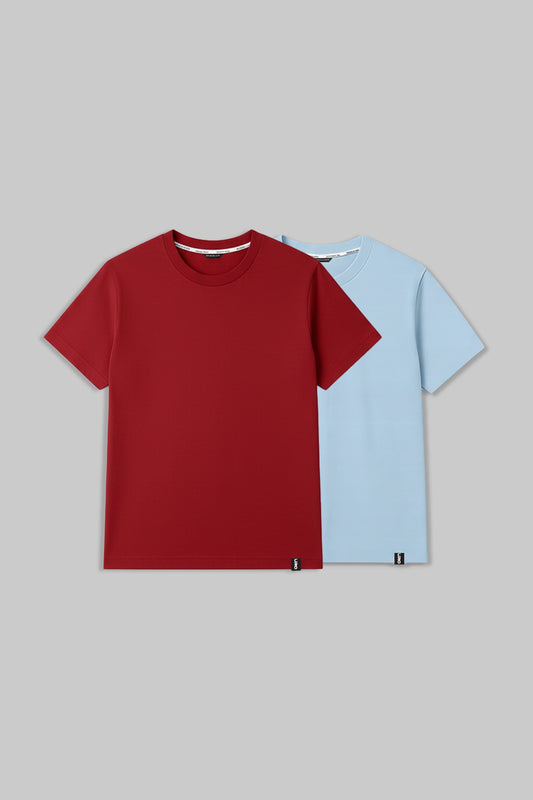 Two short-sleeve crewneck t-shirts displayed against a solid gray background. The front t-shirt is a solid deep red, and the t-shirt behind it is a solid light blue.
