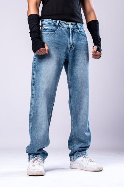 Full-body front view of a person wearing light-wash blue baggy jeans with a black top and black arm sleeves, with their hands clenched into fists.