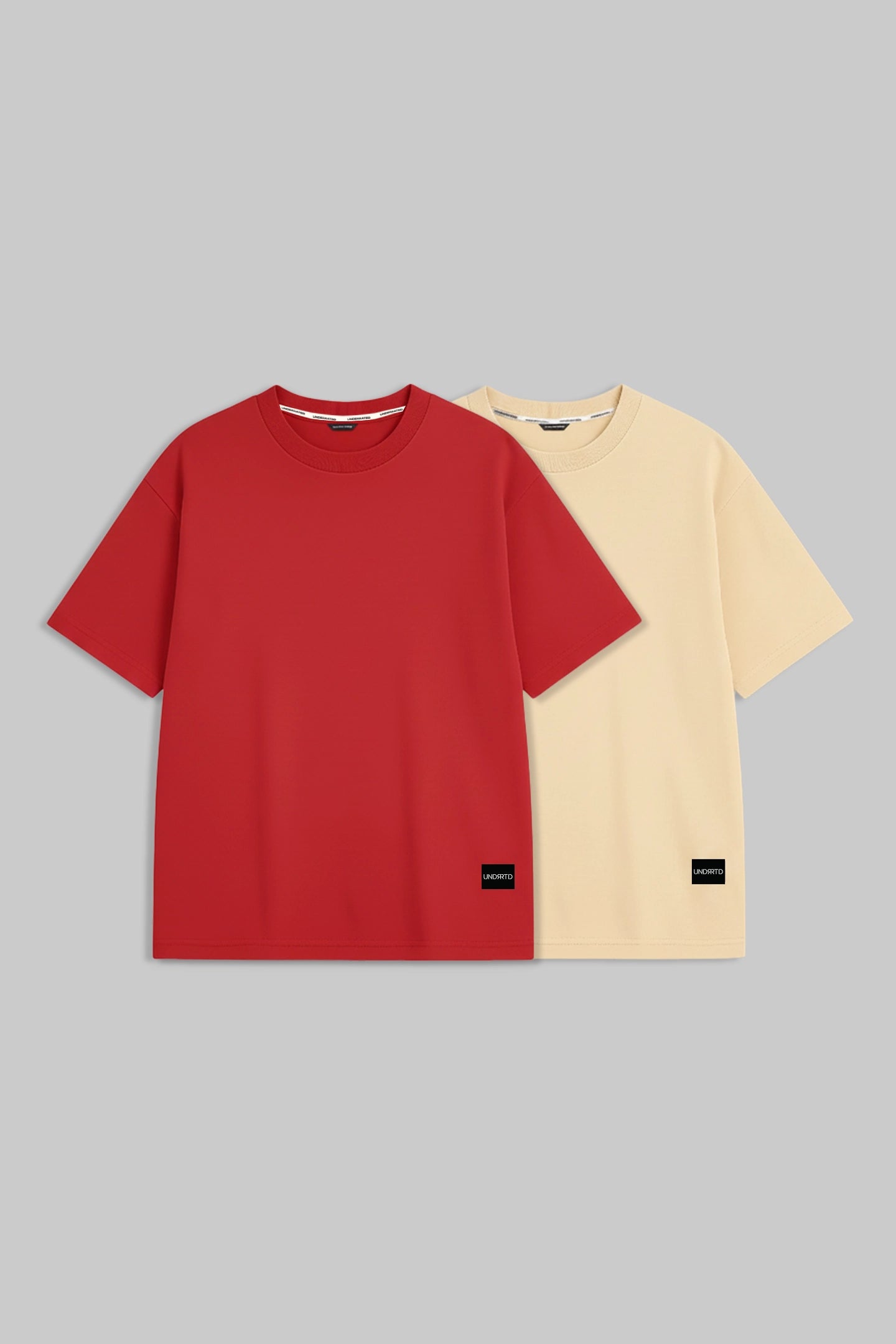 Two short-sleeve crewneck t-shirts displayed side-by-side on a solid gray background. The front t-shirt is a vibrant red, and the t-shirt behind it is a pale cream/beige color.