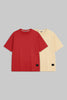 Two short-sleeve crewneck t-shirts displayed side-by-side on a solid gray background. The front t-shirt is a vibrant red, and the t-shirt behind it is a pale cream/beige color.