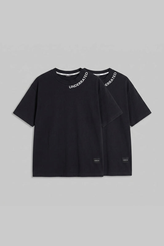 Two black short-sleeve T-shirts with layered, overlapping front designs and white 'UNDERARMED' text printed on the inner neck, displayed against a solid gray background.