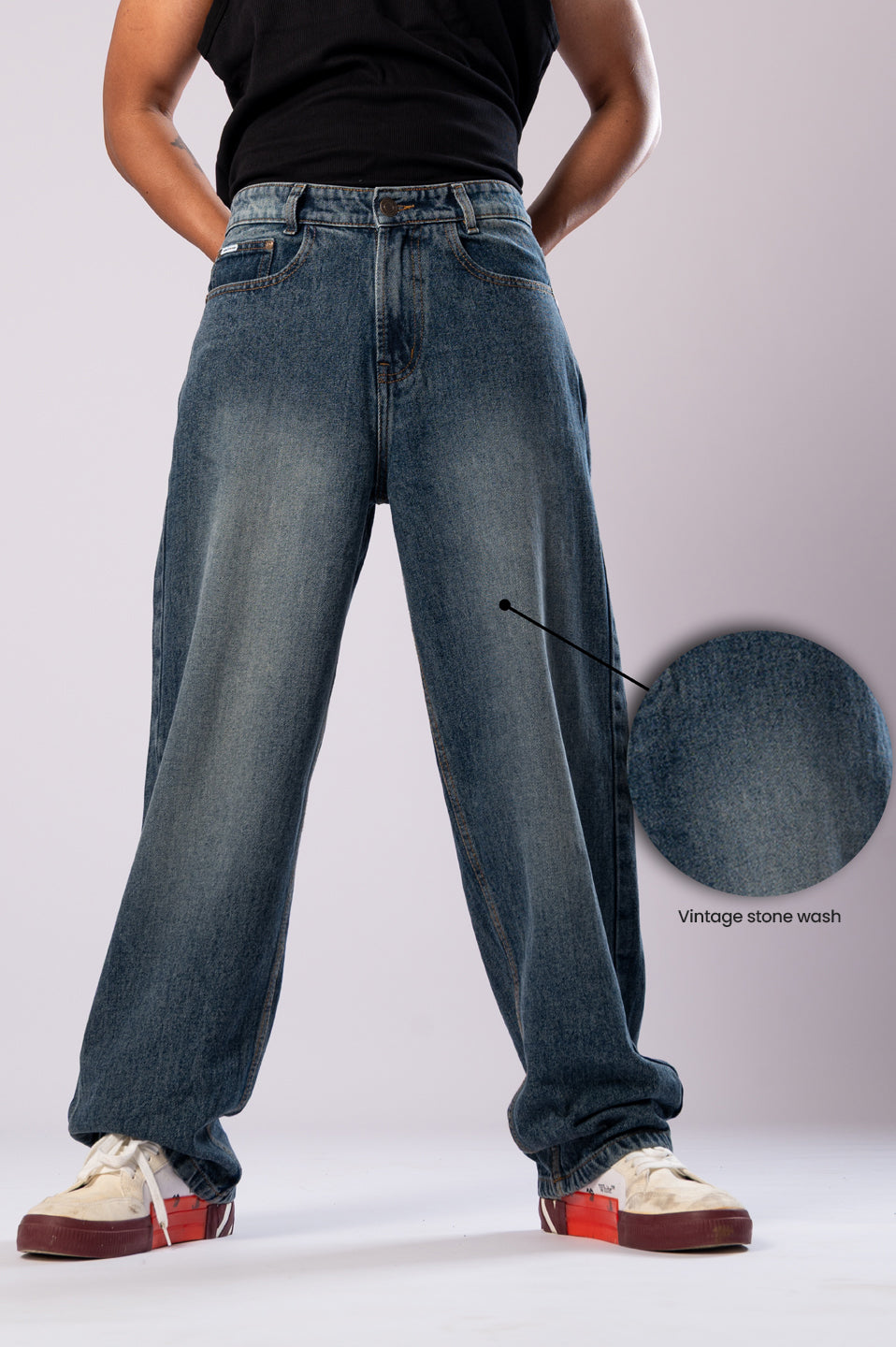 Model in dark wash baggy jeans with a skateboard, showing the full length.