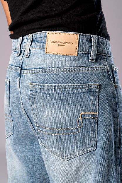 Close-up of the back of the light wash jeans, showing the leather brand patch and pocket detail.