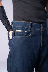 Side view of a person wearing dark-wash blue jeans with their hand in the front pocket, showing the fit and color.