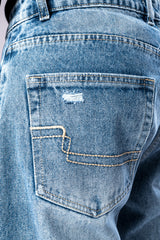 Close-up of the back pocket of light-wash blue jeans, showing detailed stitching and a small distressed rip.
