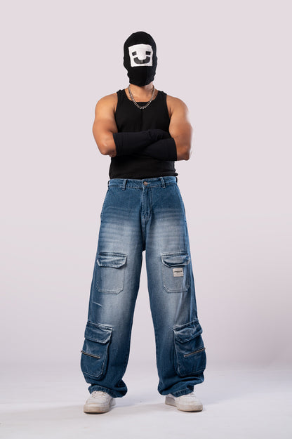 Full-body front view of a person wearing a black ski mask with a white smiley face, a black tank top, black arm sleeves, and light-wash blue baggy cargo jeans.