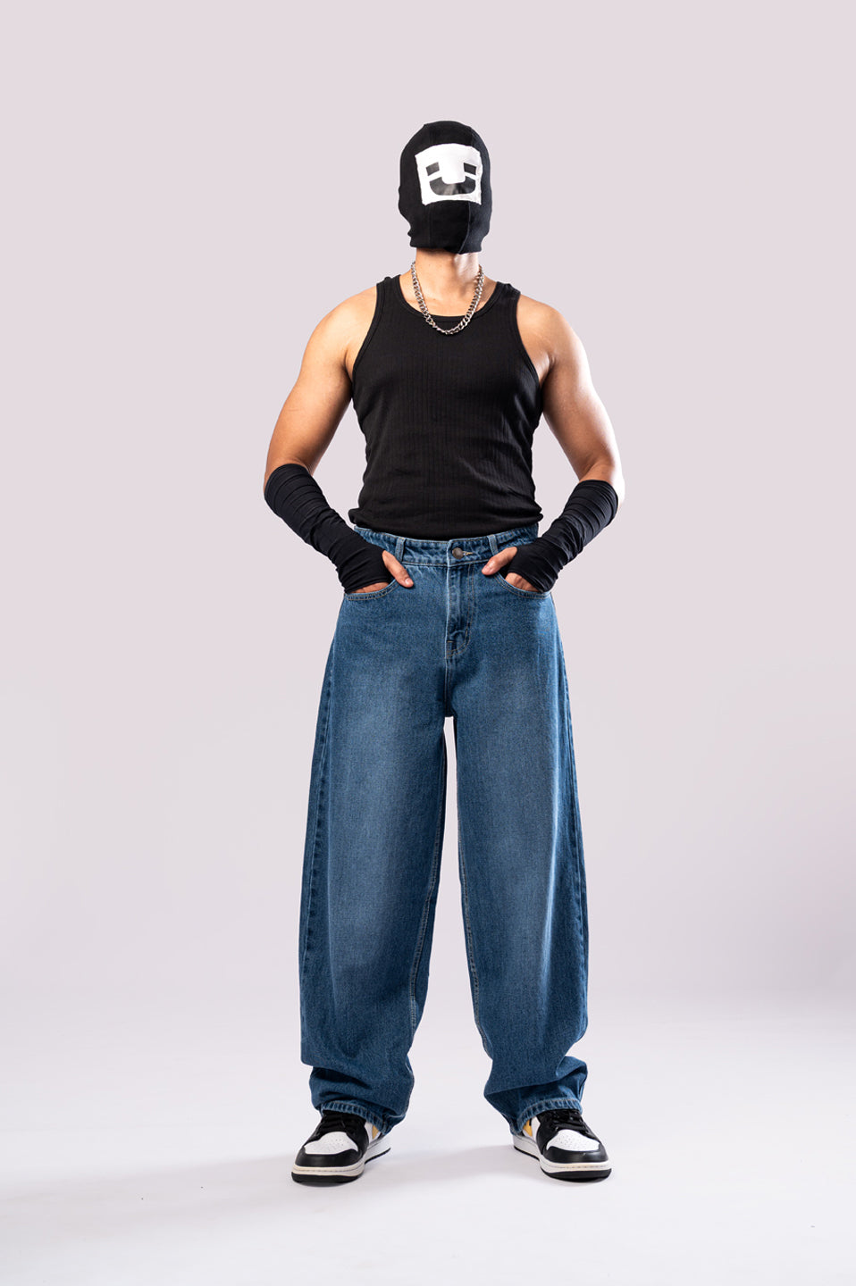 Model wearing the baggy denim jeans and a black tank top, full view.